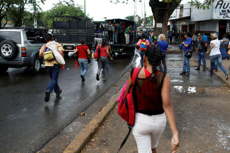 Commuters run to try to get on a cargo truck used as public transportation in Valencia, Venezuela. REUTERS/Marco Bello