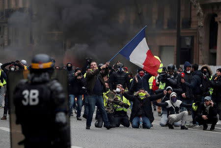 FILE PHOTO: A protester waves a French flag during clashes with police at a demonstration by the "yellow vests" movement in Paris, France, December 8, 2018. REUTERS/Benoit Tessier/File Photo