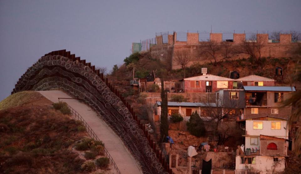 Un muro fronterizo cubierto de alambre de púas separa Nogales, en México, a la derecha, con Nogales, en Arizona, al atardecer del sábado 2 de marzo de 2019. (AP Photo/Charlie Riedel)