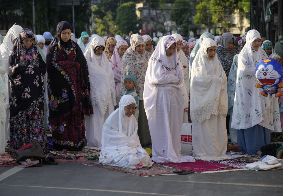 Muslim women perform a morning prayer marking the Eid al-Adha holiday on a street in Jakarta, Indonesia, Sunday, July 10, 2022. Muslims around the world will celebrate Eid al-Adha, or Festival of Sacrifice, in which sheep, goats, cows and camels are slaughtered to commemorate Prophet Abraham's readiness to sacrifice his son Ismail on God's command. (AP Photo/Tatan Syuflana)