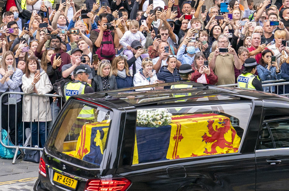 The hearse carrying the coffin of Queen Elizabeth II, draped with the Royal Standard of Scotland, passes the City Chambers on the Royal Mile, Edinburgh, Sunday, Sept. 11, 2022 on the journey from Balmoral to the Palace of Holyroodhouse in Edinburgh, where it will lie in rest for a day. (Jane Barlow/Pool Photo via AP)