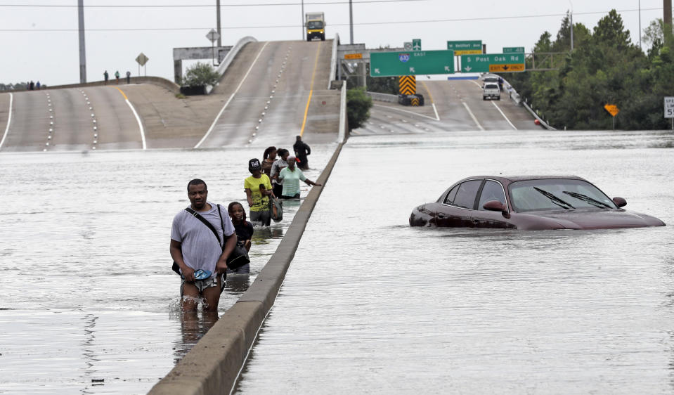 FILE - In this Aug. 27, 2017 file photo, evacuees wade through floodwaters from Tropical Storm Harvey on a section of Interstate 610 in Houston. Houston area officials expressed shock and anger on Friday, May 21, 2021, after learning that their communities, which suffered the brunt of damage from Hurricane Harvey, would be getting a fraction of $1 billion that Texas is awarding as part of an initial distribution of federal funding given to the state for flood mitigation. (AP Photo/David J. Phillip, File)