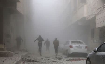 People run amid smoke from a site hit by what activists said were air strikes by forces loyal to Syria's President Bashar al-Assad in Raqqa, eastern Syria, which is controlled by the Islamic State November 27, 2014. REUTERS/Nour Fourat