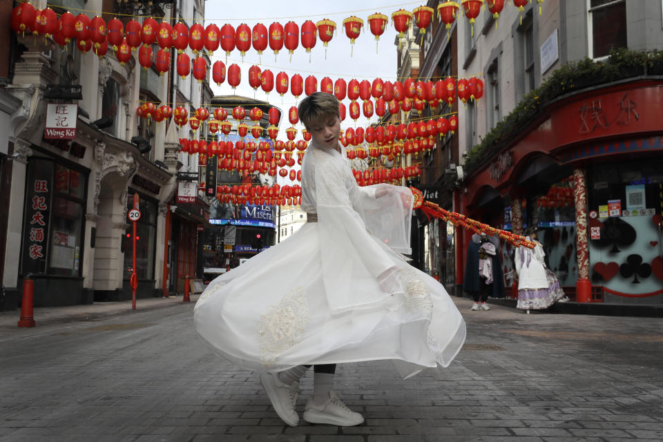 A man shows his traditional clothing as he walks through China Town in London, Thursday, Feb. 11, 2021. The Chinese New Year, which will be the Year of the Ox, will start on Friday, but due to the coronavirus pandemic many celebrations have been cancelled. (AP Photo/Kirsty Wigglesworth)