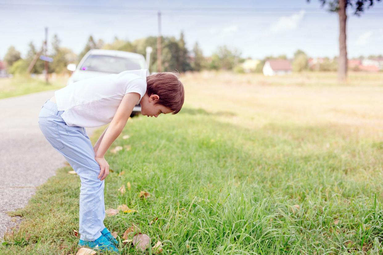 boy with motion sickness leaning over in grass