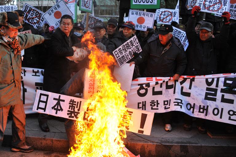 South Korean conservative activists set fire to effigies of Japanese Prime Minister Shinzo Abe during a protest to lodge a complaint against Abe visiting the Yasukuni war shrine, in Seoul on December 27, 2013