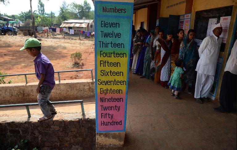 A young Indian boy plays as his mother queues to cast her vote at a polling booth inside a primary school in Shirgaon village of Pune district, some 130 kms south-east of Mumbai, on April 17, 2014