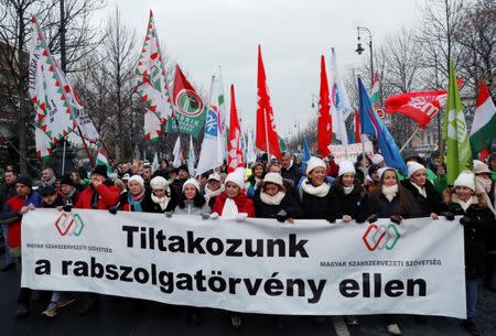 People hold a banner reading: "We protest against the slave law" as they walk in a protest against a proposed new labor law, billed as the "slave law" in Budapest, Hungary, December 16, 2018. REUTERS/Bernadett Szabo