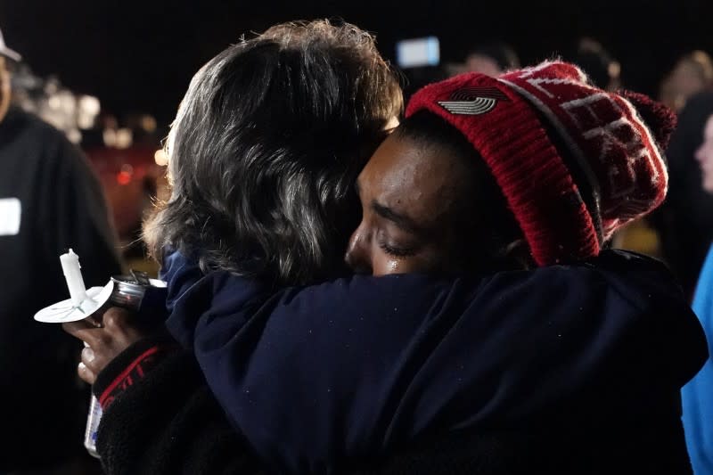 2021年12月14日，美國肯塔基州梅菲爾德消費產品公司蠟燭工廠的員工傑克森（右）在燭光悼念活動上，與另一人擁抱（美聯社）