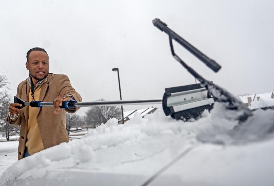 Jay Justice clears his windshield before driving Wednesday, Jan. 25, 2023 in Indianapolis, Ind. The owner of Circle City Pawn says we have to remind ourselves that we choose to live here. He says they might lose some business of people out just buying things, but customers selling their items will be out as usual. Folks that need money, he said, Òsnow doesnÕt stop those issues.Ó 