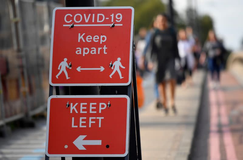 FILE PHOTO: Pedestrians walk near public health signs, whilst the reproduction "R" number of COVID-19 infections in the United Kingdom has risen and may be above 1, London, Britain