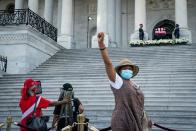 <p>A woman, waiting in line to see Lewis, raises her fist for the cameras. Lewis's flag-draped casket sits at the top of the East Front Steps of the U.S. Capitol. </p>