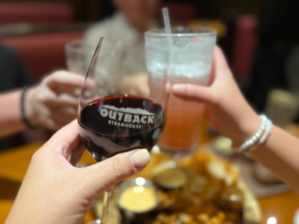 Four people at Outback steakhouse cheersing with their wine and mocktails