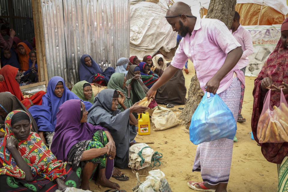 Somalis who fled drought-stricken areas receive charitable food donations from city residents after arriving at a makeshift camp for the displaced on the outskirts of Mogadishu, Somalia Thursday, June 30, 2022. The war in Ukraine has abruptly drawn millions of dollars away from longer-running humanitarian crises and Somalia is perhaps the most vulnerable as thousands die of hunger amid the driest drought in decades. (AP Photo/Farah Abdi Warsameh)