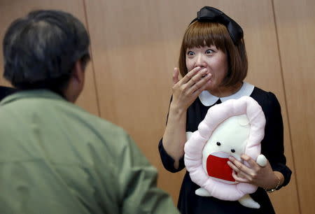 Japanese artist Megumi Igarashi (R), known as Rokudenashiko, holding her vagina-inspired artwork, reacts to a photographer after a news conference following a court appearence in Tokyo April 15, 2015. REUTERS/Toru Hanai