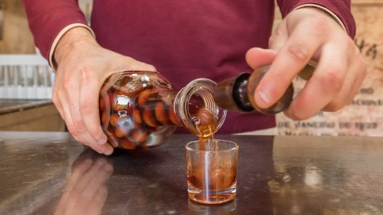 Bartender pouring red liquid into shot glass
