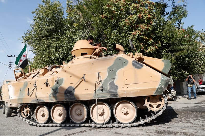 Turkey-backed Syrian rebel fighters on an armoured personnel carrier return from the Syrian border town of Tal Abyad