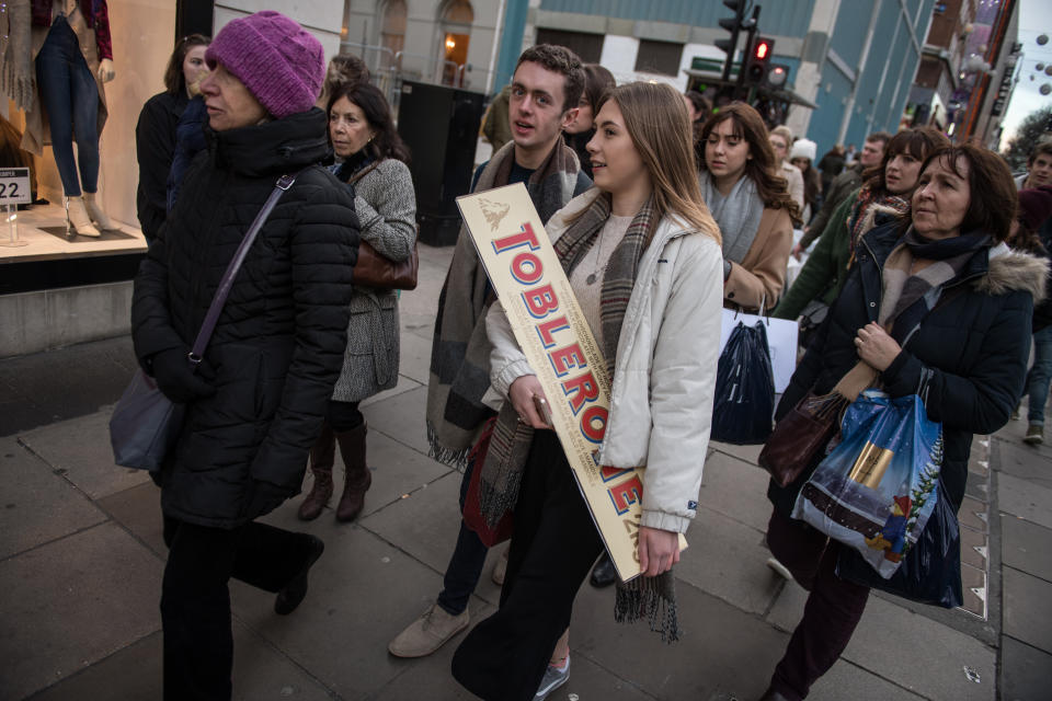 LONDON, ENGLAND - DECEMBER 09:  A shopper holds a giant Toblerone chocolate bar on Oxford Street on December 9, 2017 in London, England. With two weeks of shopping time left before Christmas, high street retailers have put on offers and attractive Christmas window displays to entice shoppers into their stores.  (Photo by Chris J Ratcliffe/Getty Images)