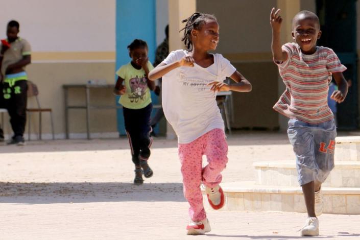 Boys and girls are playing in a yard.