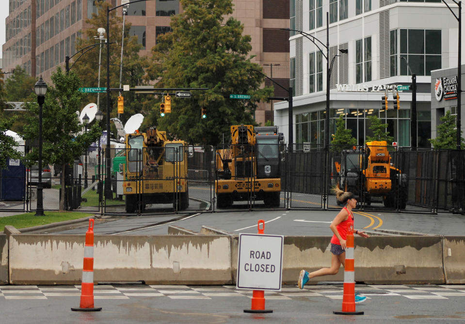 A jogger runs past a barricade prohibiting access to a street near the Charlotte Convention Center, site of the Republican National Convention in Charlotte, N.C., on Monday, Aug. 24, 2020. Charlotte-Mecklenburg police used fencing, concrete barriers and heavy vehicles to block access to streets around the convention center. (AP Photo/Skip Foreman)