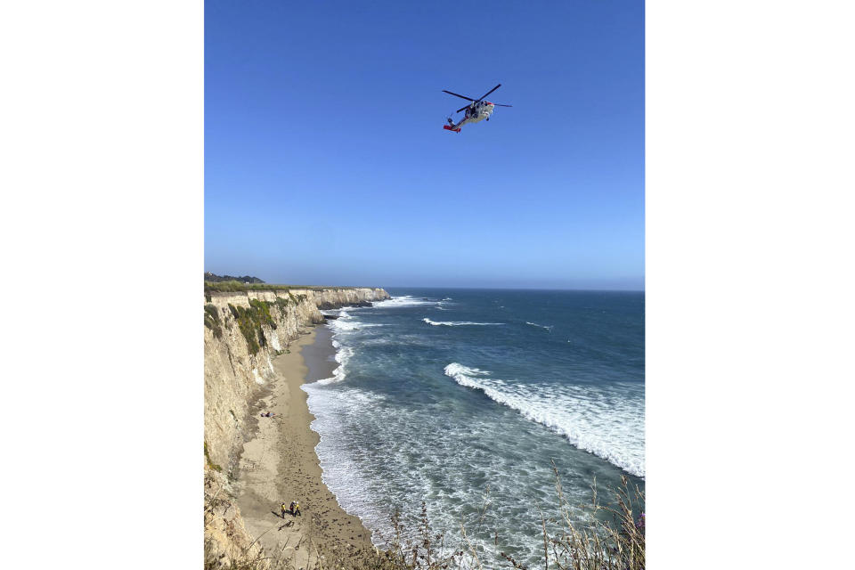 This photo taken by Cal Fire CZU, shows the scene of the rescue of a kite surfer on a beach under a cliff off the coast near Santa Cruz, Calif. Sunday, June 9, 2024. The surfer was spotted by rescue crews after they spelled out the word "help" on the beach using rocks. (Cal Fire CZU via AP)