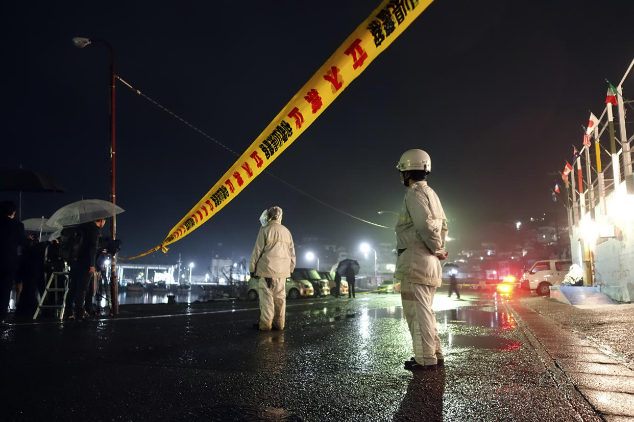 Police officers stand by a yellow rope restricting entry into the site at the Satsugasaki port where a man threw an explosive just before Prime Minister Fumio Kishida was to make a campaign speech for a local governing party candidate Saturday, April 15, 2023, in Wakayama, western Japan. (AP Photo/Mari Yamaguchi)