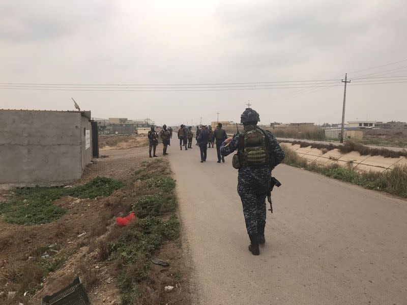 Iraqi security forces walk near a building where they found unused Katyusha rockets in Umm al-Izam