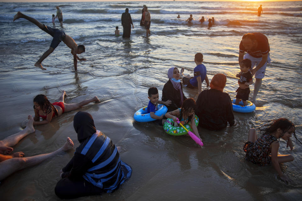 Israeli Arabs, some wearing protective face masks amid concerns over the country's coronavirus outbreak, enjoy the day on the beach during the Eid al-Adha holiday in Tel Aviv, Israel, Sunday, Aug. 2, 2020. Eid al-Adha, or the Feast of the Sacrifice, is observed by sacrificing animals to commemorate the prophet Ibrahim's faith in being willing to sacrifice his son. (AP Photo/Oded Balilty)