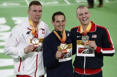 Third place finisher Piotr Lisek of Poland (L), gold medalist Renaud Lavillenie of France (C) and second place finisher Sam Kendricks of the U.S stand together on the medal's podium after the men's pole vault event at the IAAF World Indoor Athletics Championships in Portland, Oregon March 17, 2016. REUTERS/Lucy Nicholson