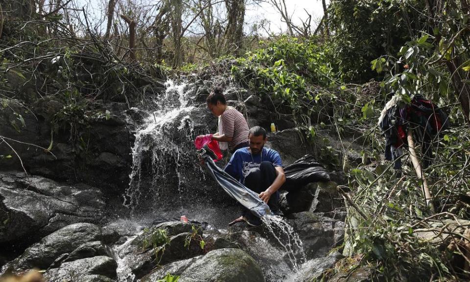 Danalys Luna and Edgardo Feliciano wash their clothes in a stream as people wait for electrical and water grids to be repaired.