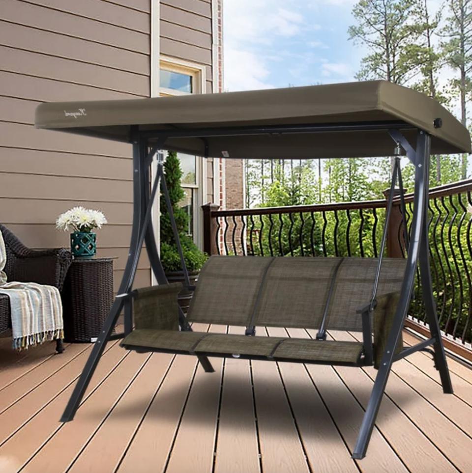 the dark green freestanding porch swing on a decorated porch