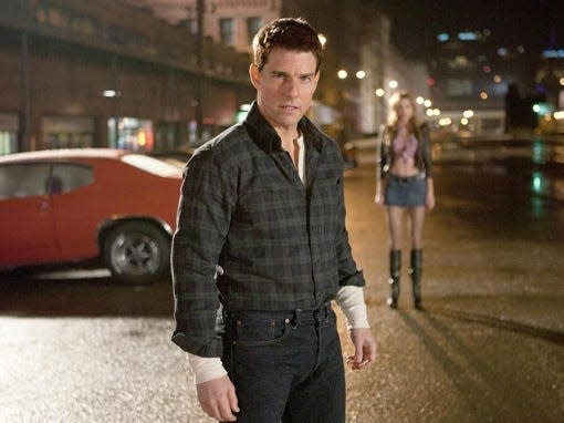 Tom Cruise in "Jack Reacher" standing in front of red car