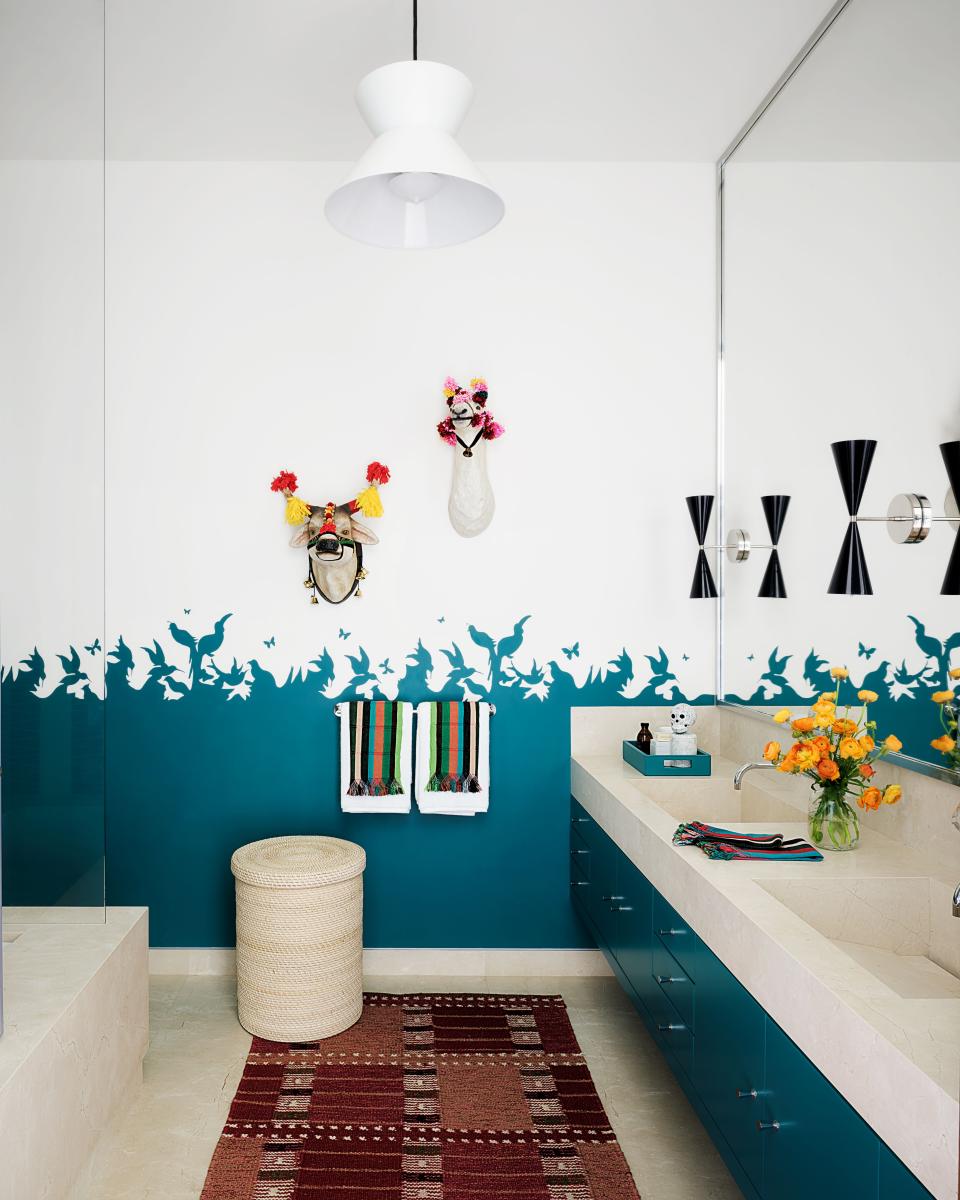 In a guest bath, Benjamin Moore's Teal Ocean adds a pop of color to cabinetry and a mural by Medina. Rejuvenation pendant; vintage Afghan rug.