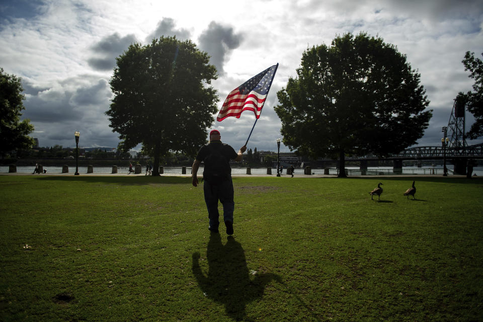 A member of the Proud Boys, who declined to give his name, carries a flag before the start of a protest in Portland, Ore., on Saturday, Aug. 17, 2019. Police have mobilized to prevent clashes between conservative groups and counter-protesters who plan to converge in the city. (AP Photo/Noah Berger)