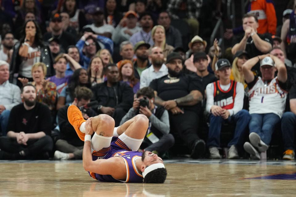 Phoenix Suns guard Devin Booker (1) reacts after being inured against the Houston Rockets during the second half at Footprint Center in Phoenix on March 2, 2024.