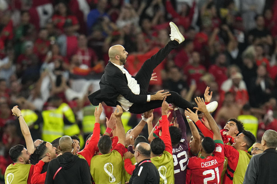 El técnico de Marruecos Walid Regragui es alzado por los jugadores tras la victoria por penales ante España en el partido por los octavos de final del Mundial, en Rayán, Qatar, el martes 6 de diciembre de 2022. (AP Foto/Julio Cortez)