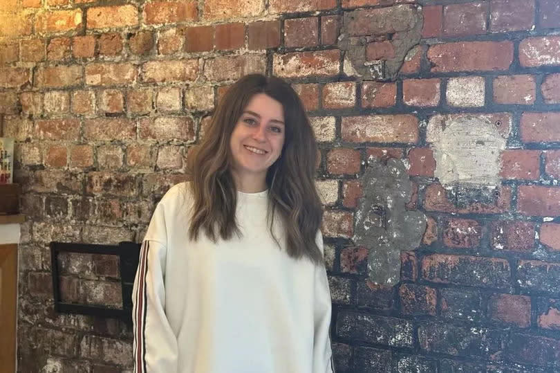 Woman standing by a wall. Located in Tramshed Tech, the woman- Sara Doust- is responsible for project management in the co-working space