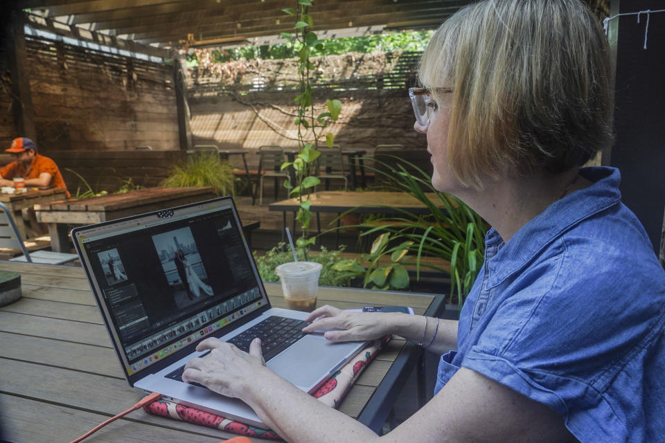 Wedding photographer Jonica Moore works from a Brooklyn cafe where she sometimes edits her wedding assignments, on Friday, July 21, 2023, in New York. Moore said that adding more social content to packages will likely require her to hire another person to help with weddings. (AP Photo/Bebeto Matthews)