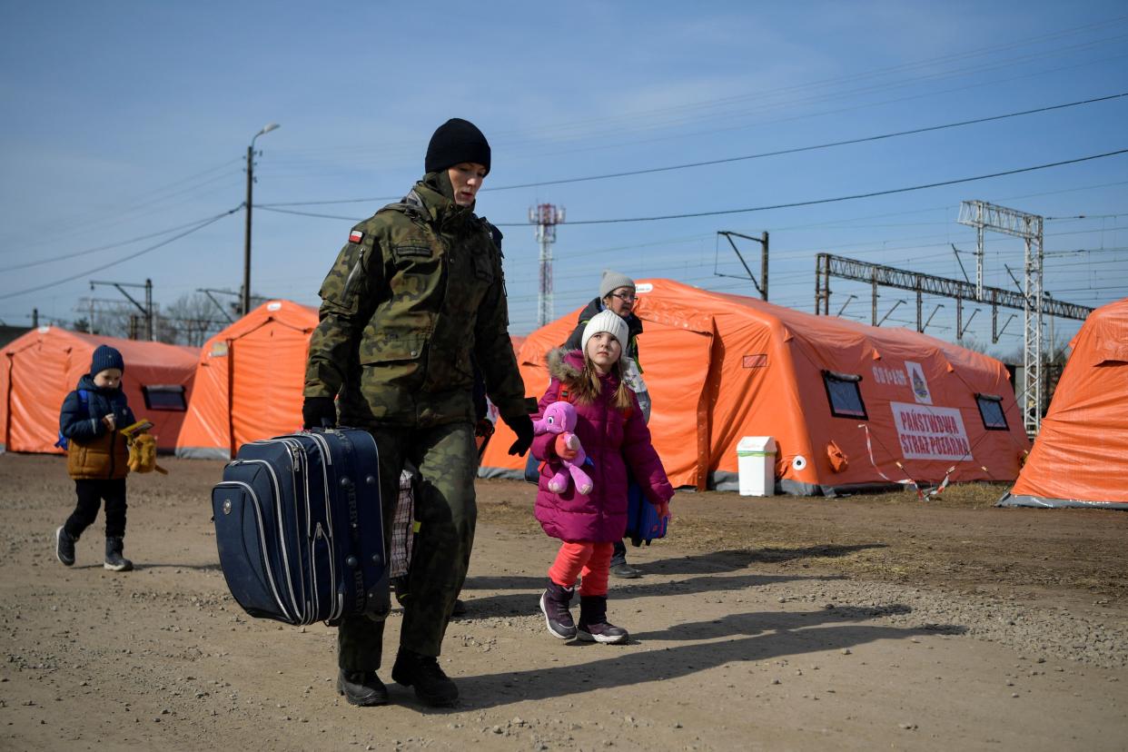 TOPSHOT - A Polish soldier helps a family on their way to take a train at the Medyka border crossing, after crossing the Ukrainian-Polish border, southeastern Poland on March 12, 2022. - More than two and a half million people have fled the 