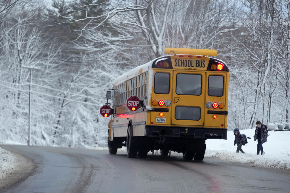 Children are picked up by their school bus following a day off due to a winter storm, Wednesday, March 15, 2023, in Poland, Maine. The storm dumped heavy, wet snow on parts of the Northeast, causing tens of thousands of power outages. (AP Photo/Robert F. Bukaty)