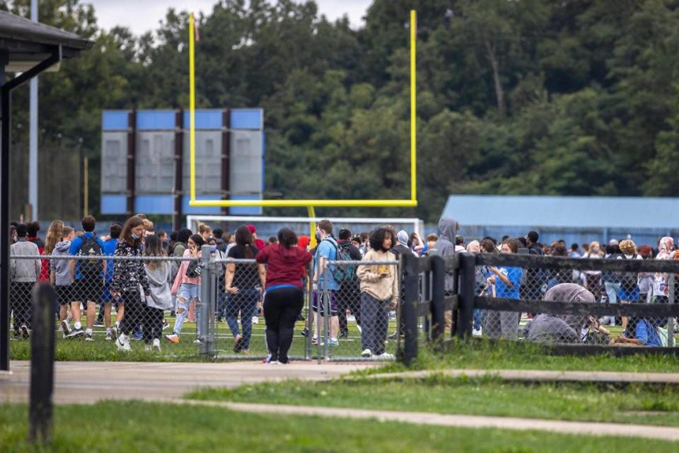 Students from Henry Clay High School stand on the football field after the school was evacuated because of a bomb threat on Tuesday, Sept. 21, 2021.