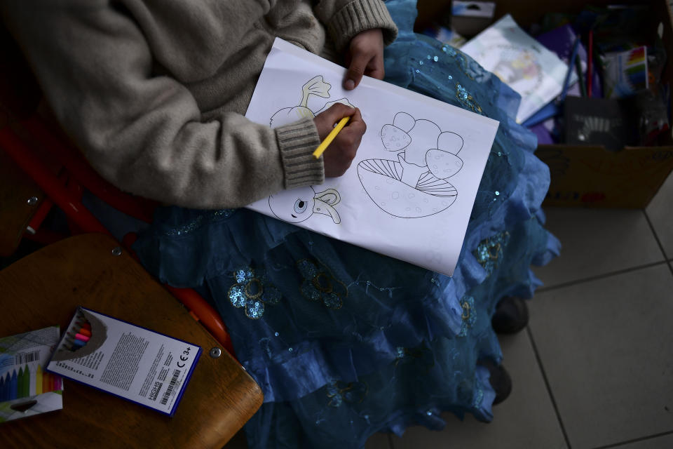 A child fleeing from Ukraine fills with a colored pencil a drawing at a temporary shelter run by the municipality and the Baptist Charity in Tiszabecs, Hungary, Friday, March 4, 2022. More than 1 million people have fled Ukraine following Russia's invasion in the swiftest refugee exodus in this century, the United Nations said Thursday. (AP Photo/Anna Szilagyi)