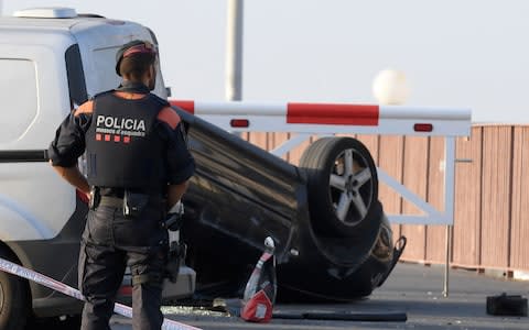 A policeman stands by a car involved in a terrorist attack in Cambrils, a city 120 kilometres south of Barcelona - Credit:  LLUIS GENE/AFP