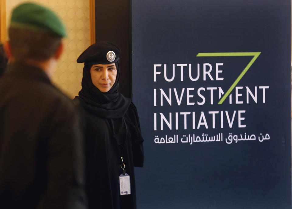 A Saudi policewoman stands near a banner for the Future Investment Initiative conference, in Riyadh, Saudi Arabia, Wednesday, Oct. 24, 2018. The high-profile economic forum in Saudi Arabia is the kingdom's first major event on the world stage since the killing of writer Jamal Khashoggi at the Saudi Consulate in Istanbul earlier this month. (AP Photo/Amr Nabil)