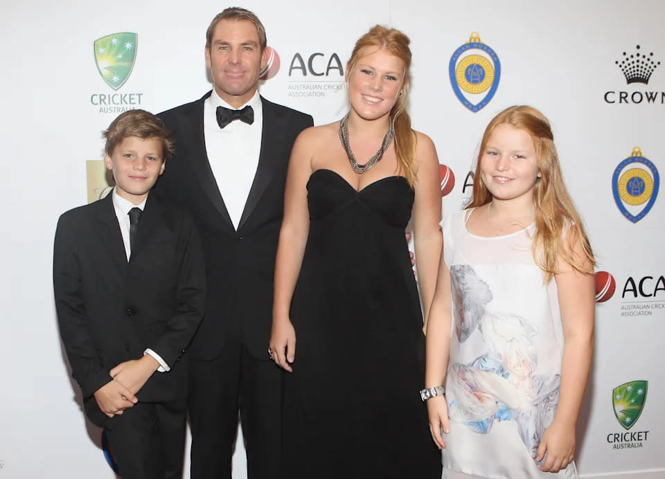 Shane Warne is seen posing for a photo with his three children.