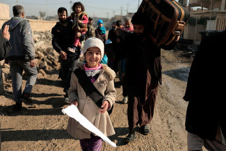 A displaced Iraqi girl hold a white flag as she flees her home in Al Mansour district, while Iraqi forces battle with Islamic State militants, in western Mosul, Iraq March 6, 2017. REUTERS/Zohra Bensemra