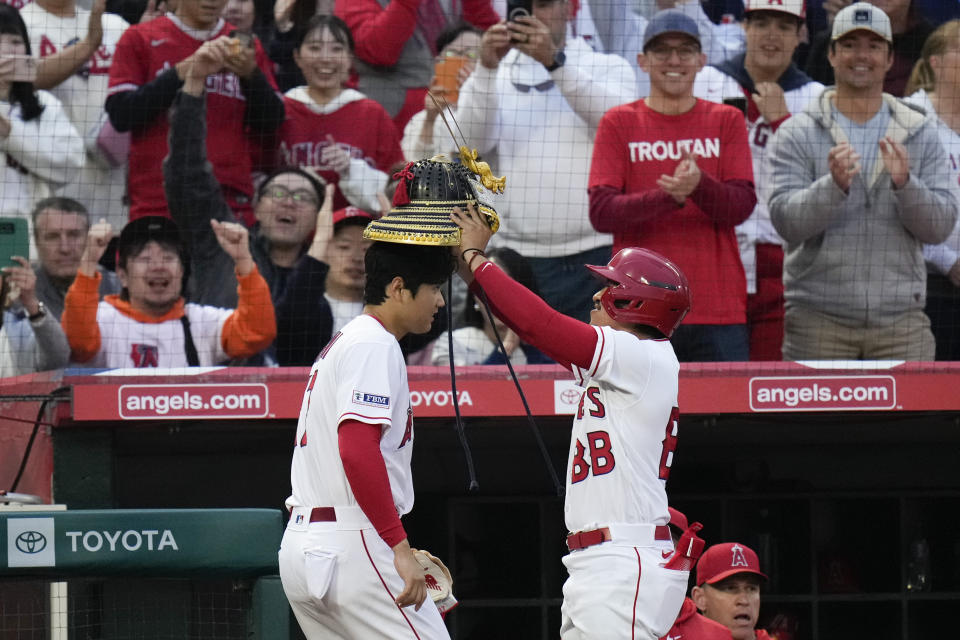 A bat boy puts a kabuto helmet on Los Angeles Angels' Shohei Ohtani, who hit a home run against the Chicago Cubs during the fourth inning of a baseball game Tuesday, June 6, 2023, in Anaheim, Calif. (AP Photo/Jae C. Hong)