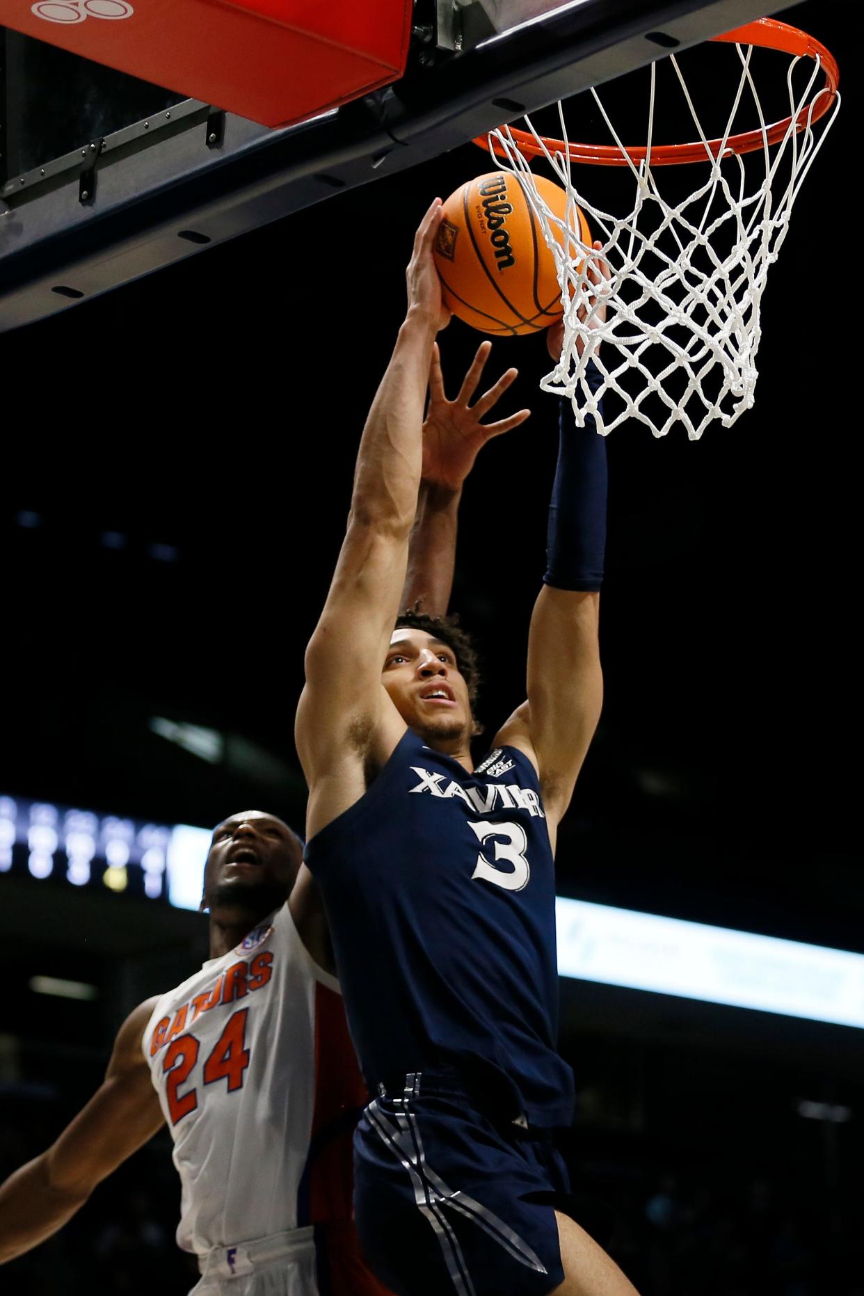 Xavier Musketeers guard Colby Jones (3) breaks away for a layup past Florida Gators guard Phlandrous Fleming Jr. (24) in the second half of the NIT Second Round game between the Xavier Musketeers and the Florida Gators at the Cintas Center in Cincinnati on Sunday, March 20, 2022. Xavier advanced in the tournament with a 72-56 win over Florida. 