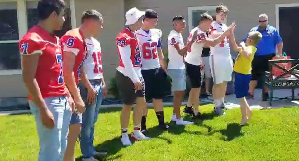 Photo showing Christian, 9, excitably high-fiving football players that came to his birthday in Meridan, Idaho.