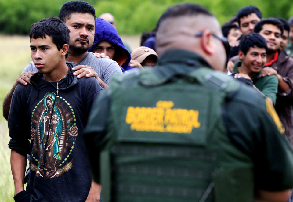 Immigrants suspected of being in the country illegally are escorted to a transportation bus after U.S. Border Patrol agents detained about 75 immigrants who'd been living in hut for several days in a brushy area Thursday April 17, 2014 near North 10 St. and Sprague St. in McAllen, Texas. Agents spent about three hours rounding up the immigrants suspected of being in the country illegally after they responded to the area. Most of the immigrants are believed to be from Central America. (AP Photo/The Monitor, Gabe Hernandez)